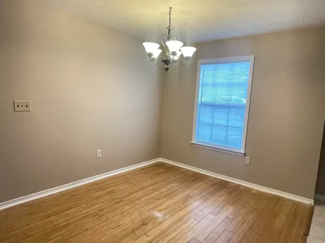 a view of a room with wooden floor and chandelier