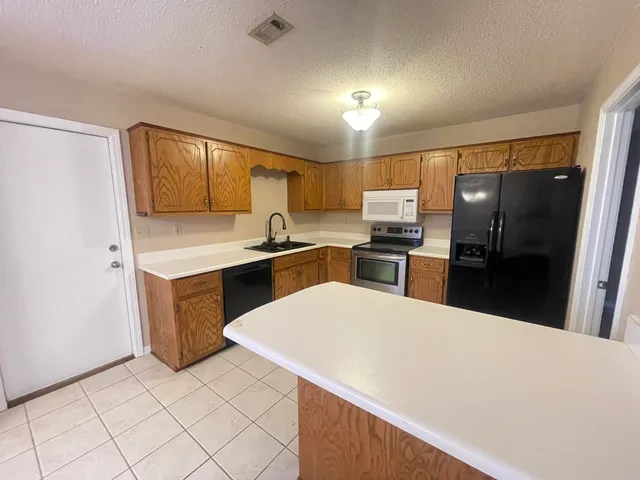a large kitchen with a sink stainless steel appliances and cabinets