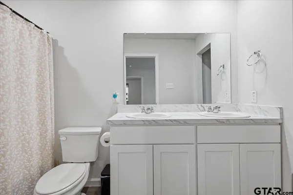 a bathroom with a granite countertop toilet sink and mirror