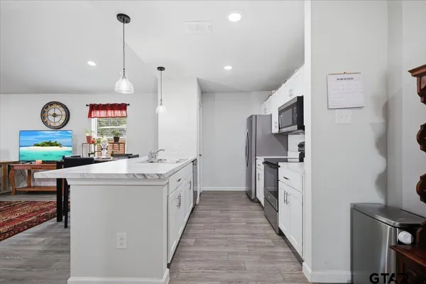 a kitchen with stainless steel appliances granite countertop a sink a stove and a wooden floors