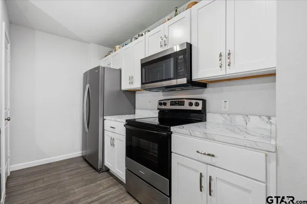 a kitchen with white cabinets stainless steel appliances and wooden floor