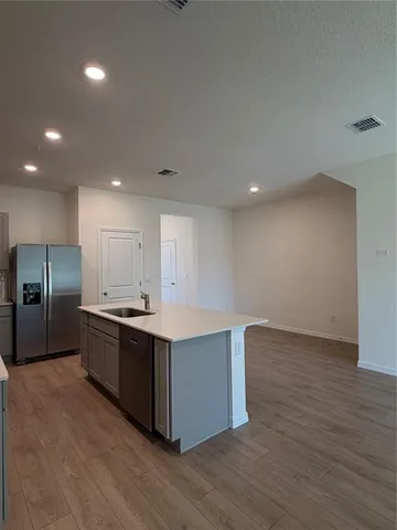 a large kitchen with stainless steel appliances a large counter top and a wooden floor