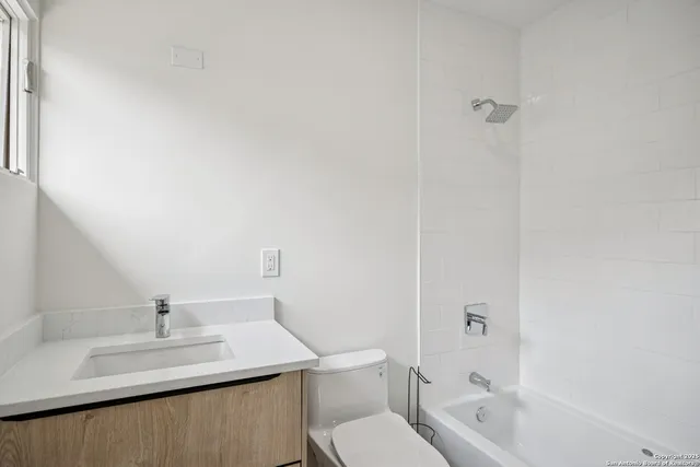 a bathroom with a granite countertop sink a toilet and shower