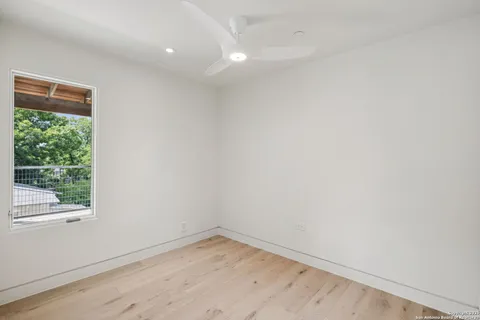 a view of empty room with wooden floor and fan