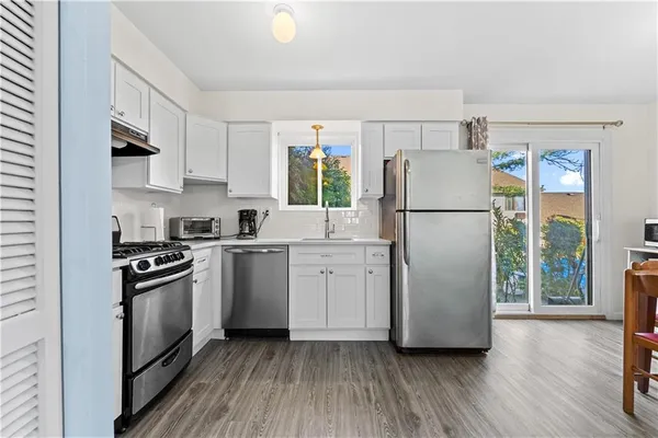 a kitchen with a refrigerator a stove a sink and a wooden floor