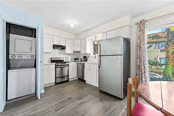 a kitchen with a refrigerator a stove top oven and white cabinets