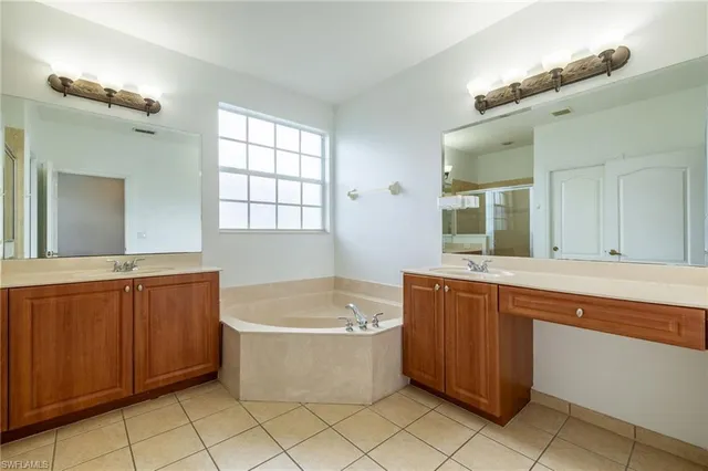 a bathroom with a bathtub a sink a mirror and a window