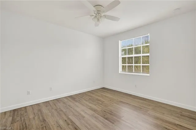 an empty room with a window and a ceiling fan