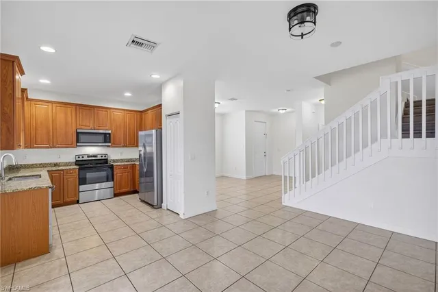 a kitchen with stainless steel appliances kitchen island granite countertop a refrigerator and a stove top oven