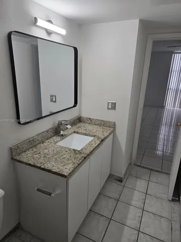 a bathroom with a granite countertop sink and a mirror