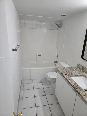 a bathroom with a granite countertop sink a toilet and shower