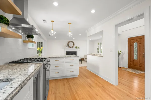 a kitchen with a sink dishwasher a stove and white cabinets with wooden floor