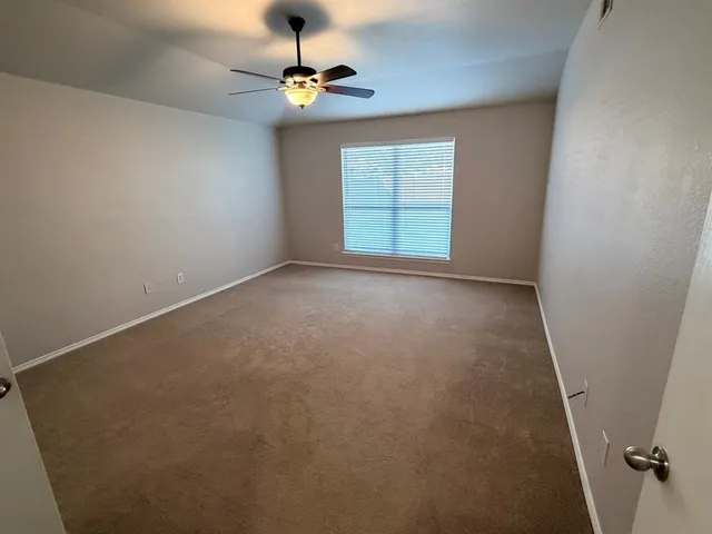 an empty room with windows and fan
