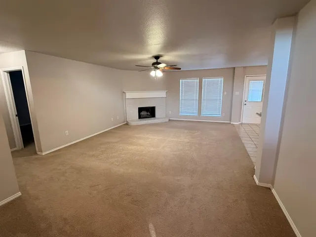 an empty room with chandelier fan and windows