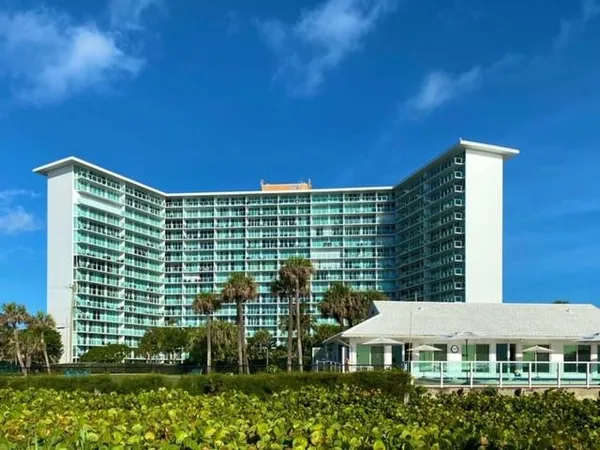 a view of house with garden and tall tress