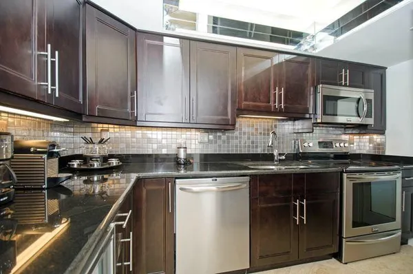 a kitchen with stainless steel appliances granite countertop a refrigerator and a stove