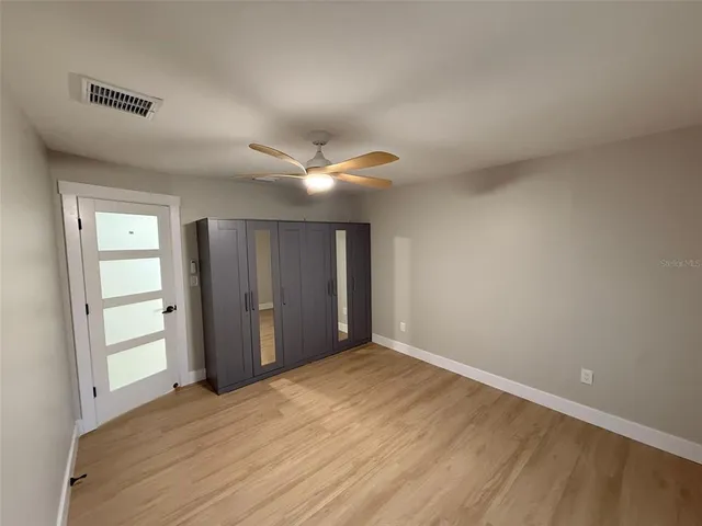 an empty room with wooden floor closet and windows
