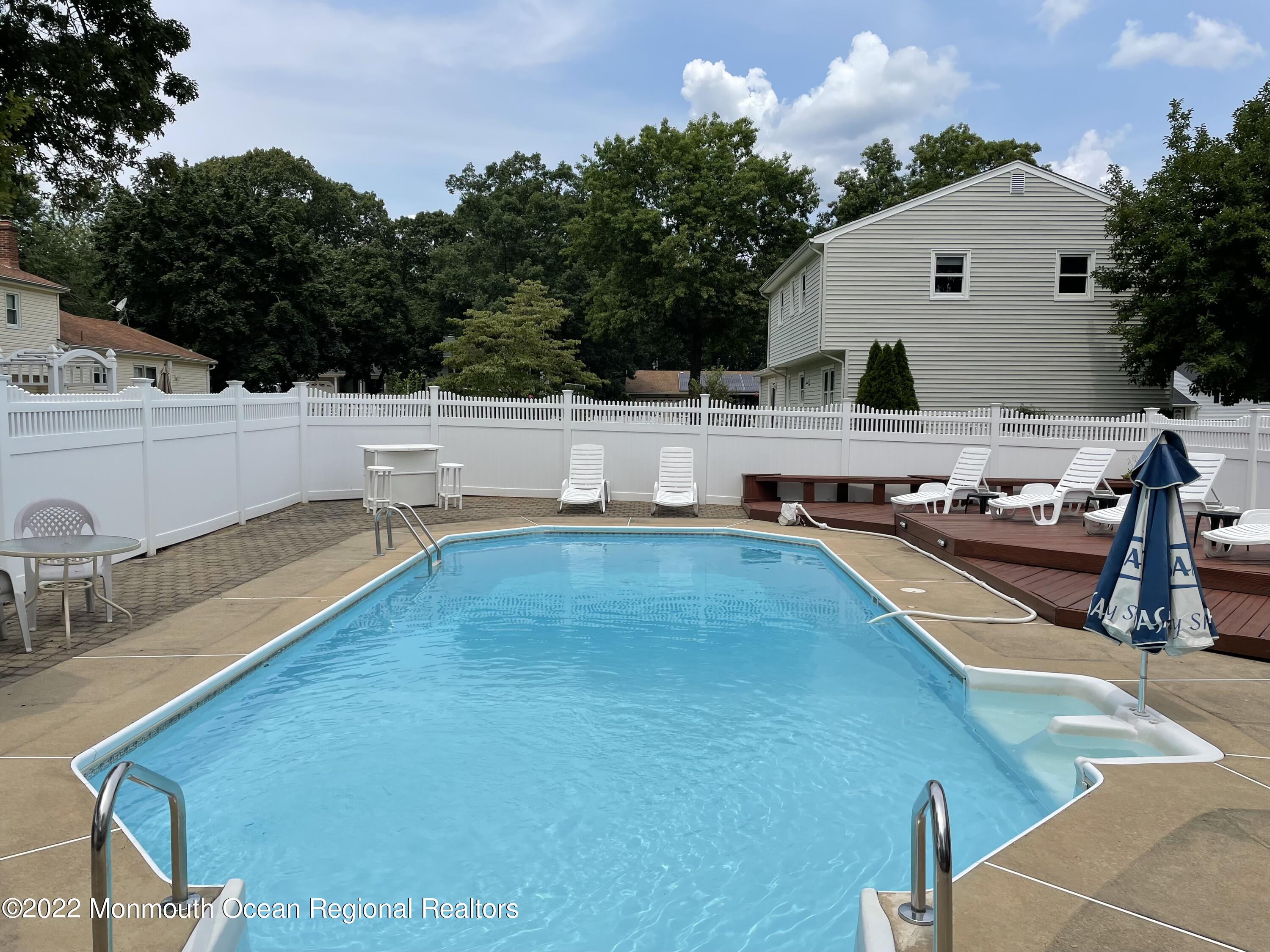 104 Pear Street, Unit WINTER Oakhurst, NJ 07755 - Photo 15 of 17 a view of a house with pool and chairs