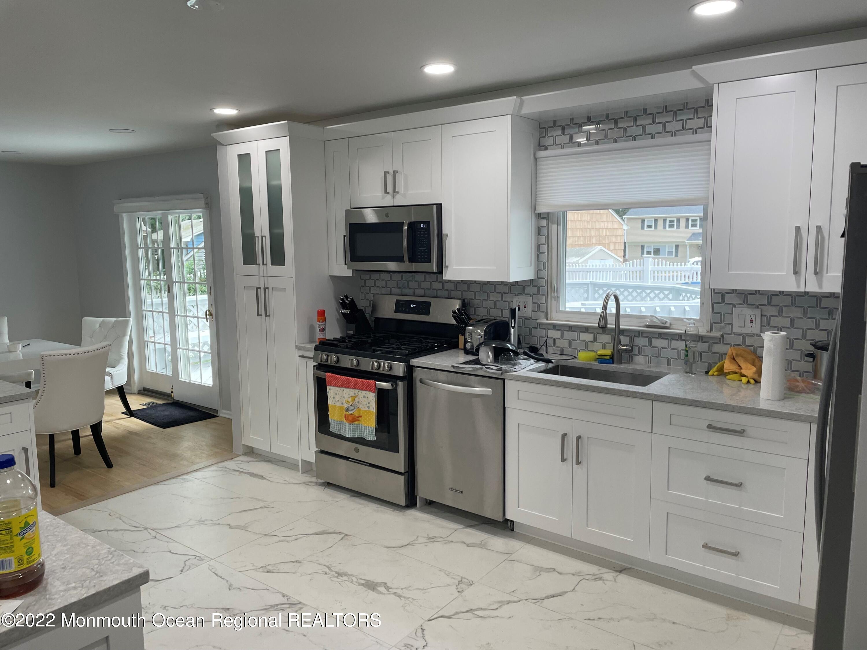 104 Pear Street, Unit WINTER Oakhurst, NJ 07755 - Photo 5 of 17 a kitchen with stainless steel appliances granite countertop a stove top oven a sink a counter space and cabinets