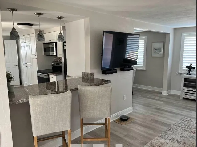 a living room with furniture a flat screen tv and a wooden floor