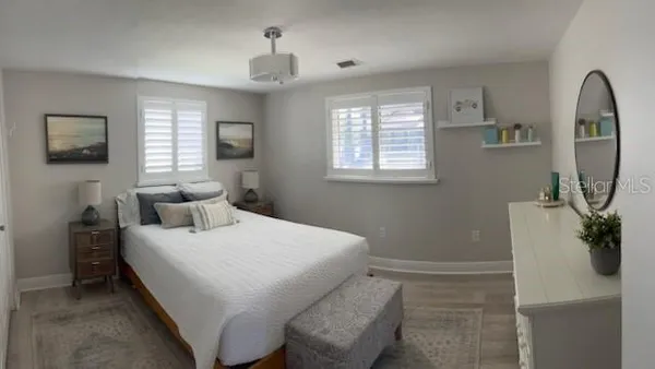 a bedroom with a bed a mirror on the dresser and a window