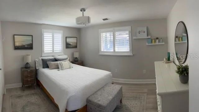 a bedroom with a bed a mirror on the dresser and a window