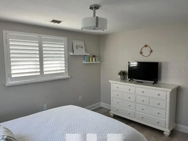 a bedroom with a bed and a flat tv screen on dresser
