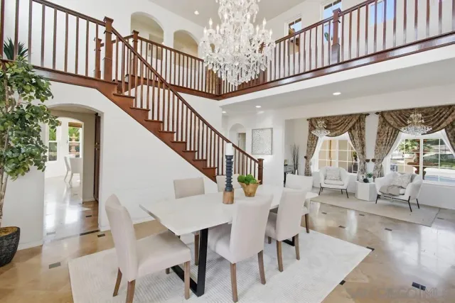 a kitchen with stainless steel appliances kitchen island granite countertop a dining table chairs and white cabinets