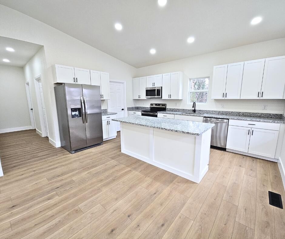 432 Englewood Road Madisonville, TN 37354 - Photo 3 of 13 a large kitchen with stainless steel appliances granite countertop a stove a sink dishwasher a refrigerator and white cabinets with wooden floor