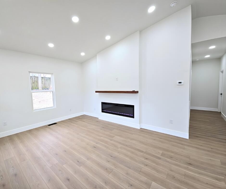 432 Englewood Road Madisonville, TN 37354 - Photo 4 of 13 an empty room with wooden floor and fireplace