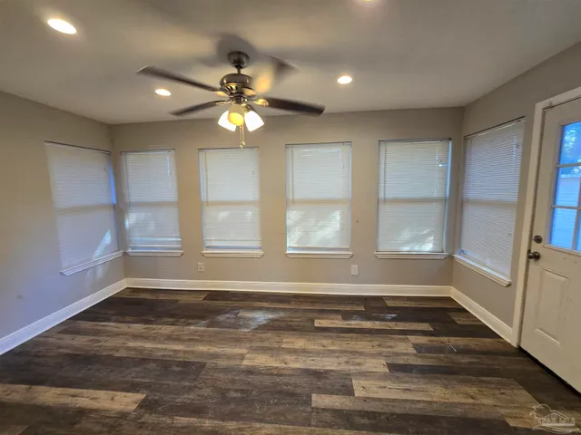 a view of an empty room with a window and wooden floor