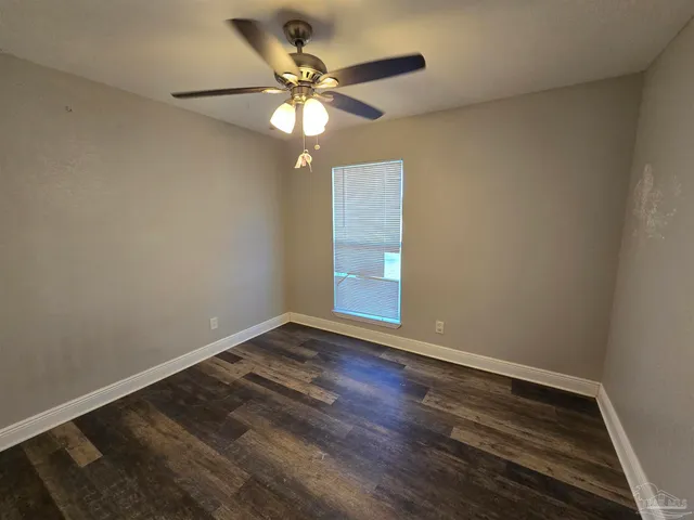 an empty room with wooden floor and chandelier fan