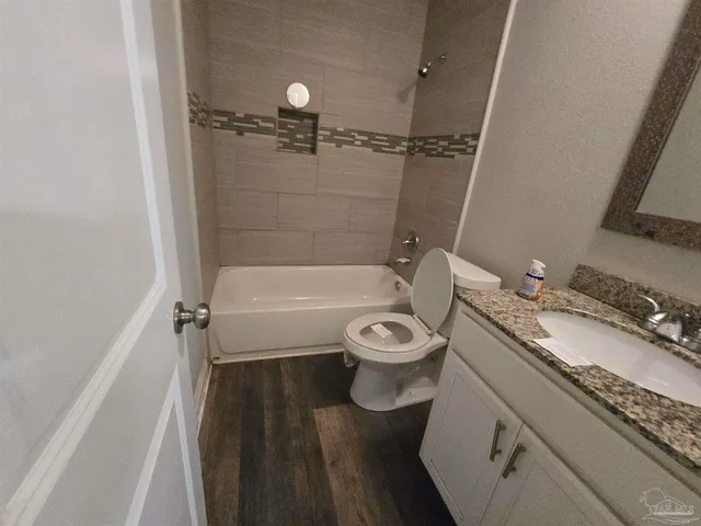 a bathroom with a granite countertop toilet sink and mirror