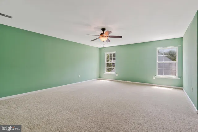 a view of an empty room with a window and a kitchen