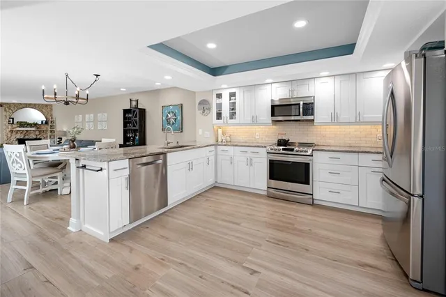 a kitchen with stainless steel appliances granite countertop a stove top oven a sink dishwasher and a refrigerator with wooden floor