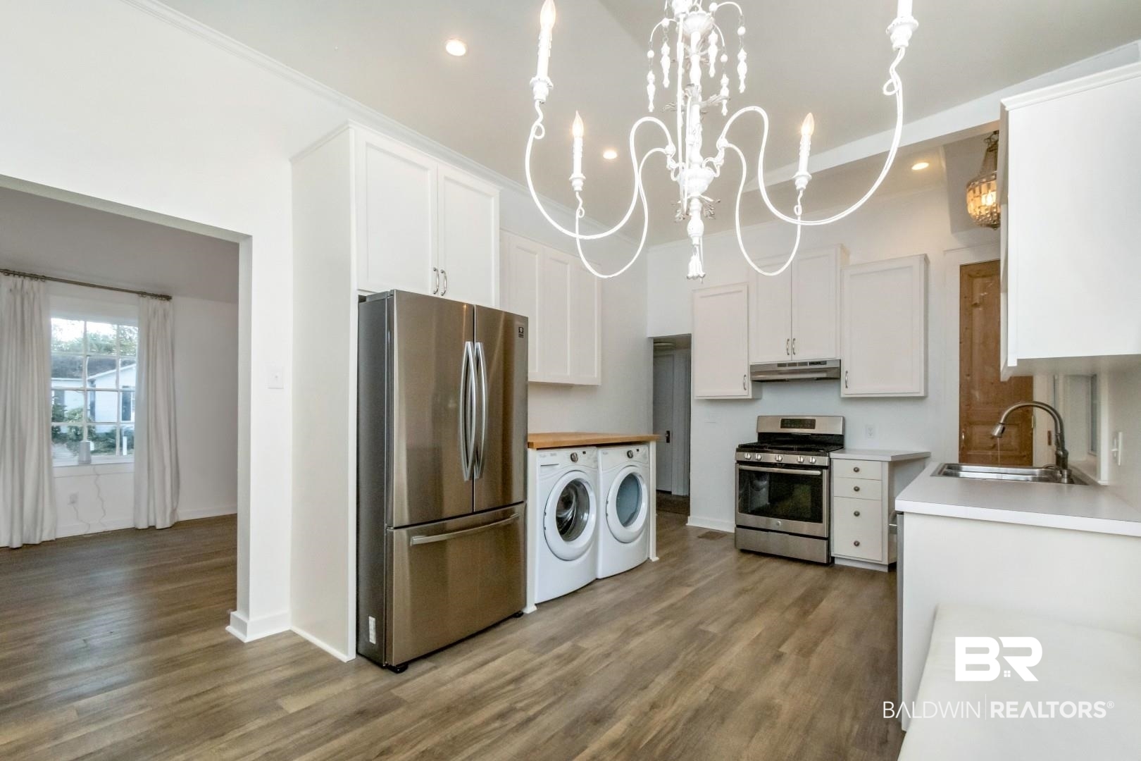16 Princess Anne Road Mobile, AL 36608 - Photo 17 of 40 Kitchen featuring stainless steel appliances, white cabinets, hanging light fixtures, light wood-type flooring, and washer and clothes dryer