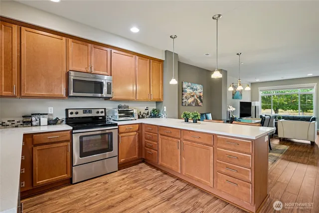 a kitchen with stainless steel appliances granite countertop a stove a sink and a refrigerator with wooden floors