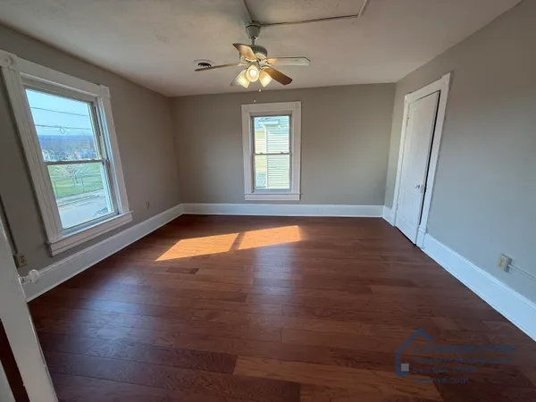 an empty room with wooden floor and windows