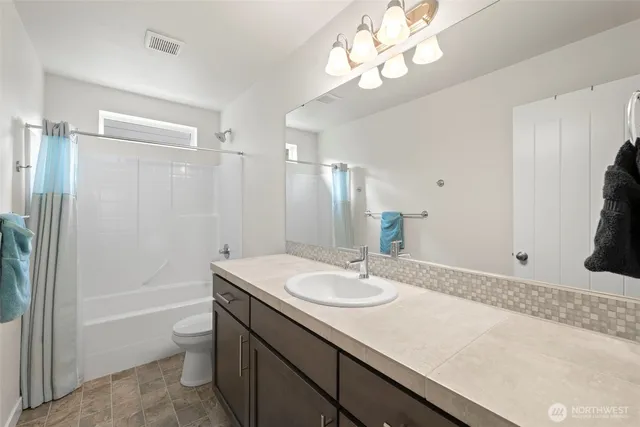 a bathroom with a sink a toilet and a large mirror