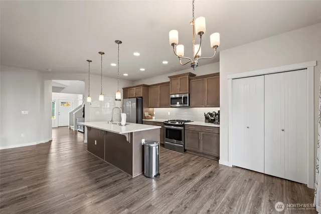 a large kitchen with kitchen island a stove a sink a center island and a wooden floor