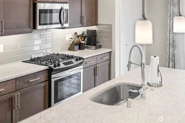 a kitchen with granite countertop a sink stainless steel appliances and cabinets
