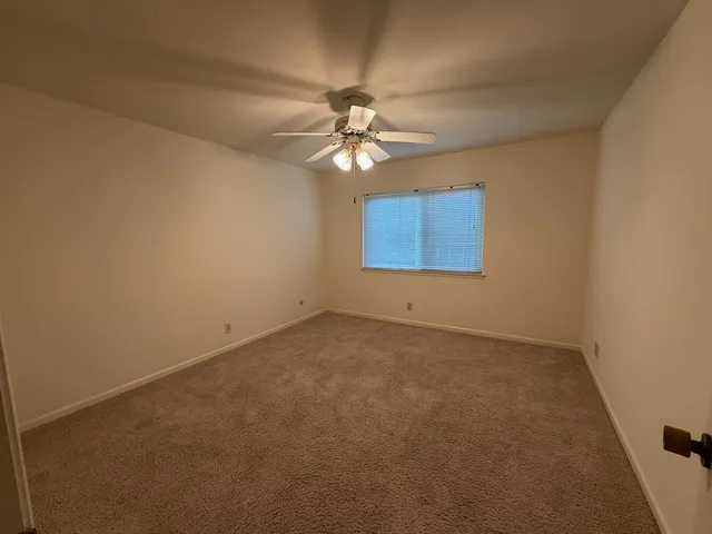 an empty room with windows and fan