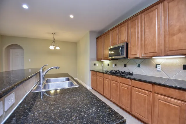 a kitchen with granite countertop wooden cabinets a sink and dishwasher