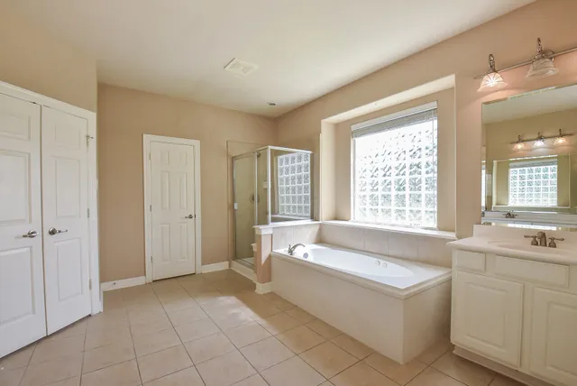 a spacious en suite bathroom with a tub sink and mirror