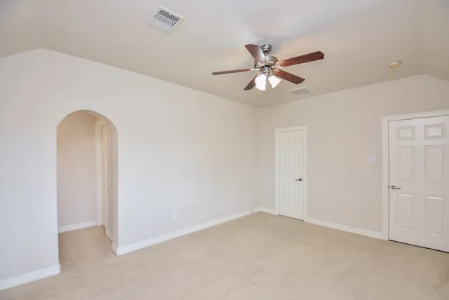 an empty room with closet and a ceiling fan