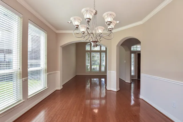 a view of a room with wooden floor chandelier and windows
