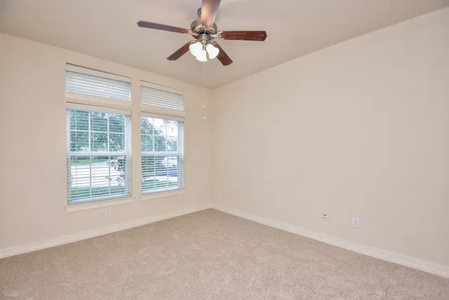 an empty room with a window and a fan