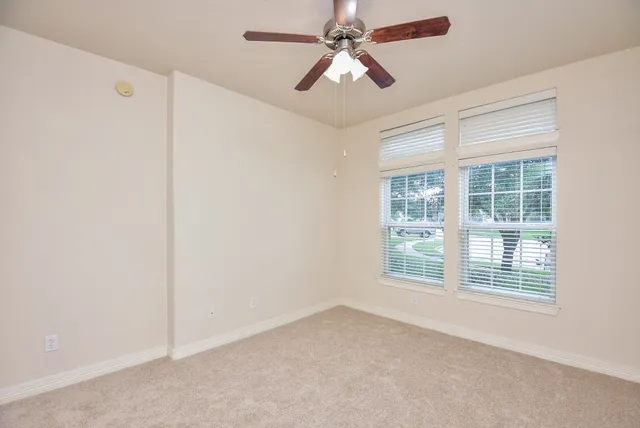 an empty room with windows and fan