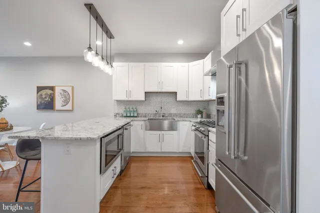 a kitchen with stainless steel appliances granite countertop a refrigerator a sink and white cabinets