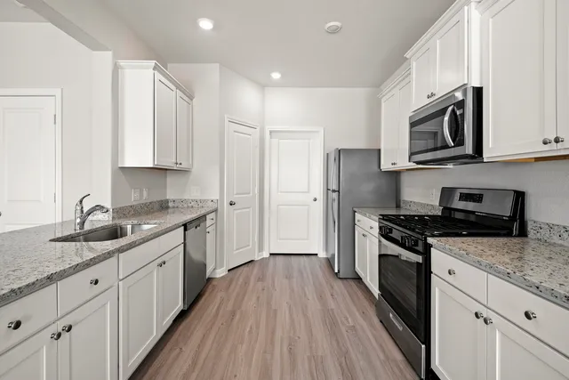 a kitchen with stainless steel appliances granite countertop a stove a sink and a refrigerator